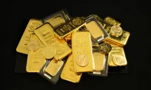 Stos prawdziwego złota: sztabki i monety o różnej wadze, błyszczące w świetle.