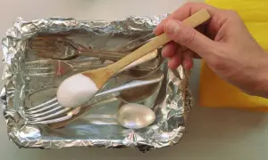 Srebrne sztućce w folii aluminiowej, na łyżce soda oczyszczona.