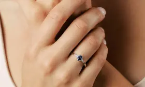 Elegancki pierścionek z owalnym szafirem i diamentami, ozdabiający dłoń.