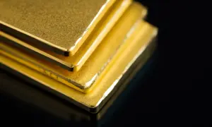 Stos złotych sztabek na czarnym tle.
