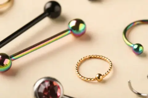 Kolekcja biżuterii do piercingu: sztangi, kółka i podkowy w tęczowych i złotych kolorach, idealne do piercingu penisa.