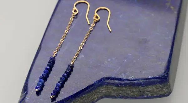 Eleganckie kolczyki z lapis lazuli na złotym łańcuszku, zakończone zapięciem bigiel.