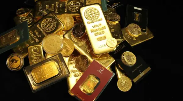 Złote sztabki i monety, w tym 1-kilogramowa sztabka, pokazują, ile waży sztabka złota.