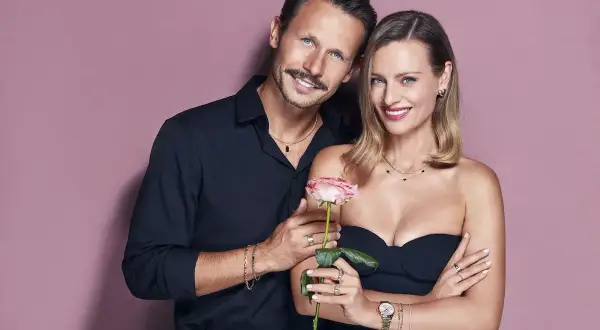Para, która reklamuje apart, trzyma różę. Elegancka kobieta i mężczyzna w czarnych strojach prezentują biżuterię.