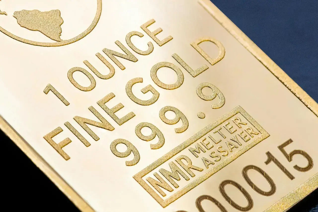 Sztabka złota z napisem "1 OUNCE FINE GOLD 999.9" i numerem seryjnym.