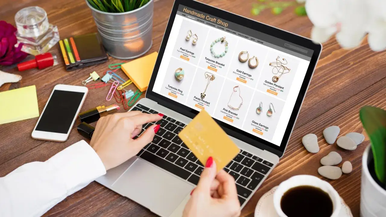 Kobieta z kartą kredytową przegląda biżuterię na laptopie, szukając inspiracji, gdzie sprzedawać biżuterię online.