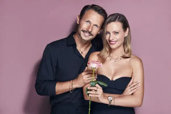 Para, która reklamuje apart, trzyma różę. Elegancka kobieta i mężczyzna w czarnych strojach prezentują biżuterię.