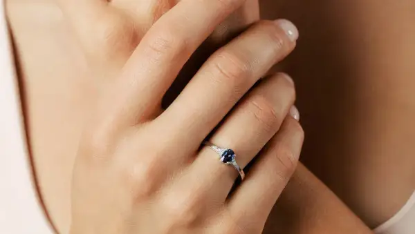 Elegancki pierścionek z owalnym szafirem i diamentami, ozdabiający dłoń.